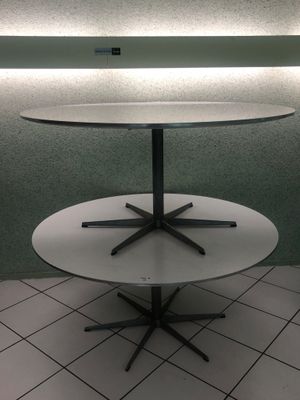 une table blanche à trois pieds noirs posée sur un sol carrelé