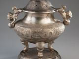 un vase en argent richement décoré, surmonté d'un oiseau