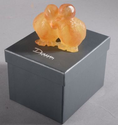 a small orange bear sitting on top of a black box