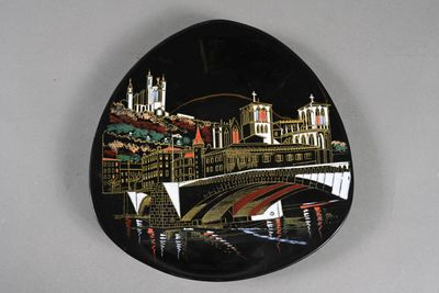 a black oval plate with a picture of a bridge and buildings on it