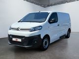 La camionnette blanche est garée dans une grande pièce aux murs blancs.