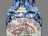 un vase orné d'un oiseau et de fleurs, posé sur un socle