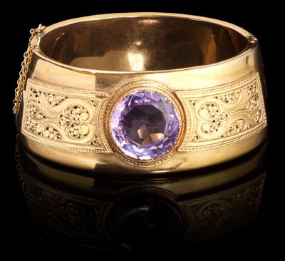 une photo d'un bracelet en or orné d'une pierre violette au centre