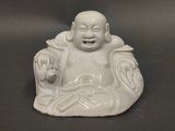 une petite statue représentant un Bouddha souriant, posée sur une table