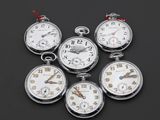 cinq montres de poche en argent avec des cadrans blancs sur un fond noir