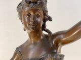 bronze statue of a woman holding a tennis racquet on a marble base