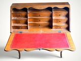 an old wooden desk with a red rug on top of it