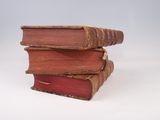 three old books stacked on top of each other on a white surface