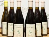 six bouteilles de vin sont alignées sur un plateau en bois