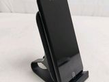 a black cell phone sitting on a stand on a bed
