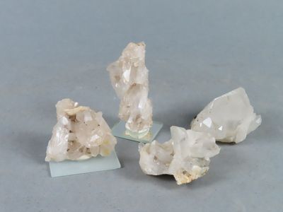 trois morceaux de quartz posés sur un socle en verre, sur une surface grise