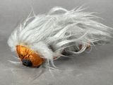 a small stuffed animal with white hair on a gray surface