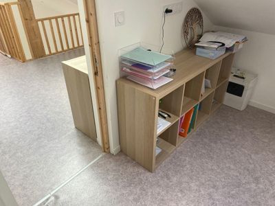 un bureau avec des livres et un ventilateur dans un coin de la pièce