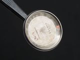 a small metal pan with a handle on a black surface