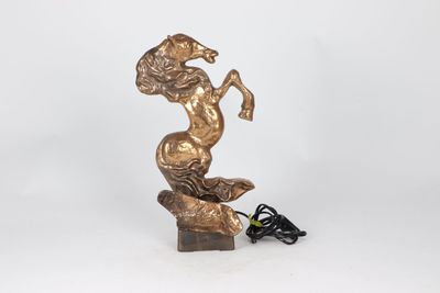 une statue en bronze représentant une femme assise sur un rocher, avec un cordon d'alimentation