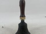 a bell with a wooden handle sitting on top of a snow covered ground