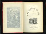 un livre ouvert posé sur une table noire, à côté d'un livre rouge