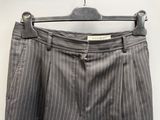 un pantalon gris à fines rayures suspendu à un cintre sur un mur blanc