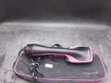 un sèche-cheveux noir et rose posé sur un sac noir