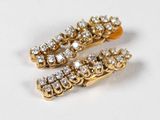 une paire de barrettes en or et diamants posées sur un fond blanc