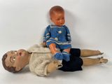 a small doll sitting on top of a doll laying on the ground