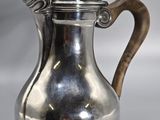 an antique silver coffee pot with a wooden handle on a table