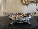 a silver bowl with flowers in it sitting on a table