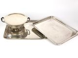 deux plateaux en argent et un plateau muni d'un couvercle, posés sur une surface blanche