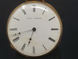 a small gold pocket watch with roman numerals on it