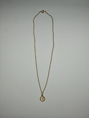 un collier en or avec un pendentif circulaire au bout d'une chaîne
