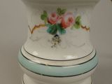 a white and blue vase with a gold top