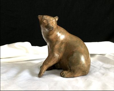 une statue représentant un chat assis sur un drap blanc