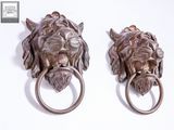 pair of bronze lion head door knockets on a white background