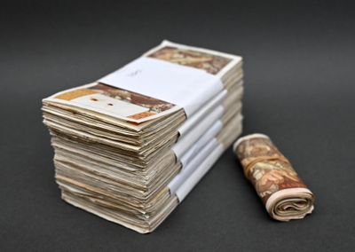 une liasse de billets posée à côté d'un rouleau de papier enroulé