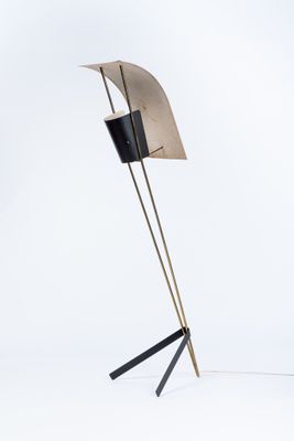 un lampadaire noir et doré surmonté d'un abat-jour noir