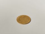 a gold coin on a white surface with a white background