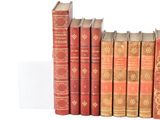 several old books are lined up in a row on a white surface