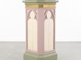 une image représentant un socle rose et vert surmonté d'une horloge