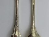 two silver spoons and a fork on a table
