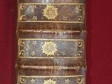 an old book sitting on top of a red cloth covered table