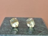une paire de boucles d'oreilles en topaze jaune posées sur un socle en marbre