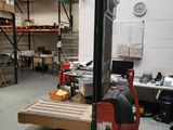 un chariot élévateur dans un entrepôt où s'alignent des rayonnages remplis de cartons