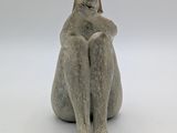 statue of a cat sitting on its back with its head on its paws