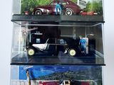 trois petites voitures dans une vitrine posée sur une surface blanche
