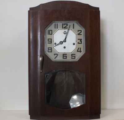 une horloge en bois accrochée au mur, près du mur