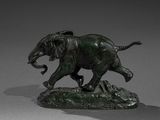 bronze statue of an elephant on a rock on a gray surface