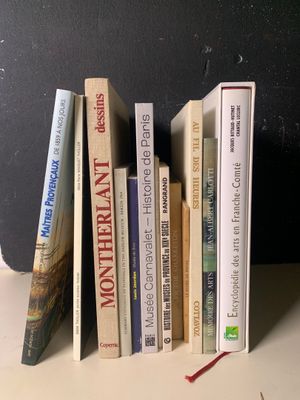 Plusieurs livres sont alignés sur une étagère devant un mur noir