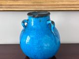 un vase bleu posé sur une table devant un tableau