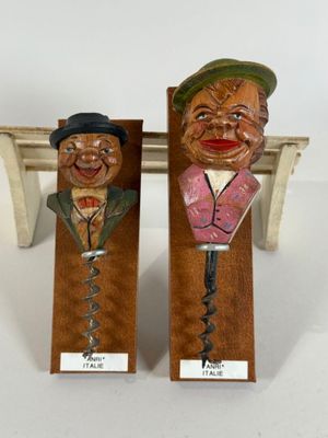 pair of wooden wine openers with faces on them on a table