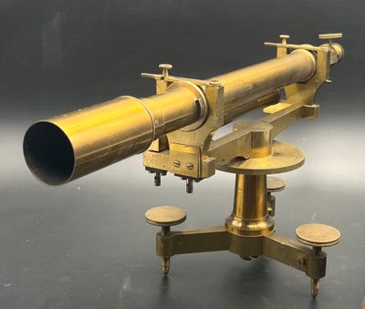 un télescope ancien en laiton posé sur un socle, sur une surface noire